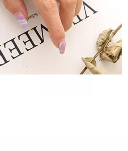 Gros plan sur ongles adhésifs dégradés mauves avec motifs nuages blancs et paillettes argent