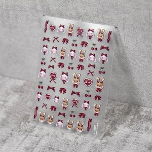 Macro detail of embossed nail stickers featuring deep red bows and cute rabbit designs