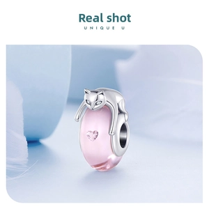 Macro detail of S925 silver cat charm with pink glass bead and heart-shaped zircon