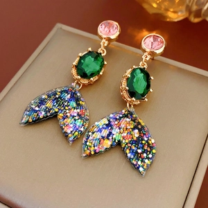 Vintage mermaid fish tail earrings with pink crystal and green gemstones on a gold box