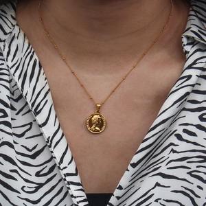 Close-up of golden vintage coin pendant featuring Elizabeth II portrait on link chain