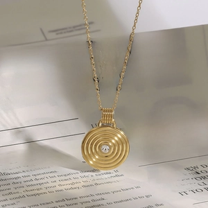 Macro shot of gold concentric circle pendant with a sparkling crystal on vintage paper