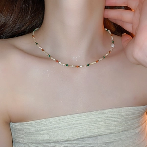 Gros plan d'un collier de perles colorées avec perles blanches et accents orange et vert