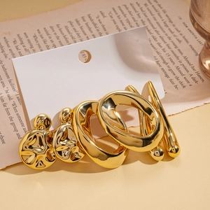 Detail of gold-plated lava texture studs and twisted hoop earrings set on aesthetic background