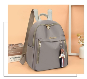 Detail of grey Oxford fabric backpack with gold zipper and a cute bear toy charm