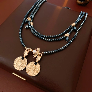 Detail of vintage gold-tone beads and layered necklace with bee pearl charm and round pendants