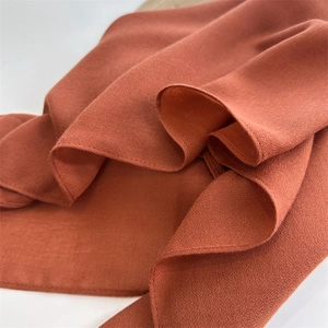 Close-up of rust red cotton linen fabric showing texture and elegant soft drape