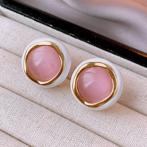 Detail view of pink cat eye opal earrings with gold metal plating in a jewelry box