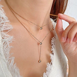 Detail of a gold double-layer Y-shaped necklace featuring three sparkling round zircons
