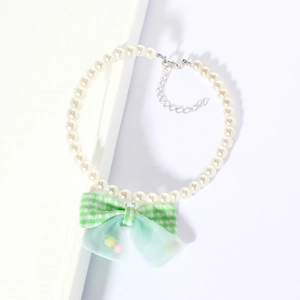 Close-up of pearl pet necklace with green plaid bow and adjustable silver metal chain