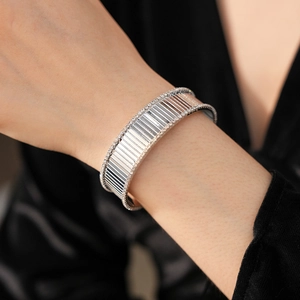 Gros plan détaillé d'un bracelet manchette argenté avec rayures et cristaux scintillants