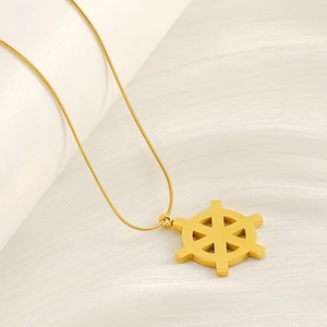 Gros plan d'un pendentif gouvernail doré sur un fond en tissu blanc texturé élégant