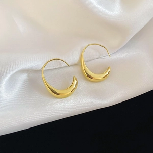 Polished 14k gold plated oval hook earrings displayed on elegant white silk fabric