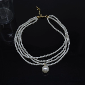 Detail of multi-layer pearl necklace with a single large pearl drop and gold clasp