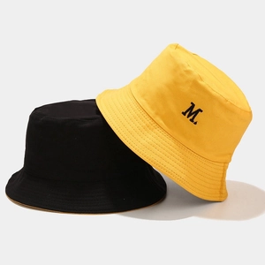 Dettaglio di cappelli a secchiello nero e giallo con ricamo della lettera M di qualità