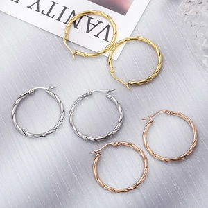Macro shot of 30mm twisted hoop earrings in gold, silver, and rose gold finishes