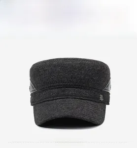 Detail of dark grey wool flat cap featuring a metal shield emblem and leather trim edging