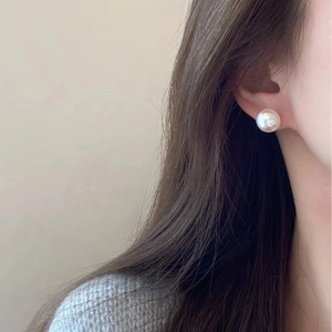 Elegant white pearl stud earring on model, minimalist vintage style with silver needle
