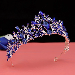 Close-up of silver tiara crown with blue marquise rhinestones on a decorative pedestal