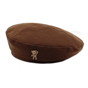 Detailed texture of dark brown wool beret featuring a cute 3D teddy bear ornament