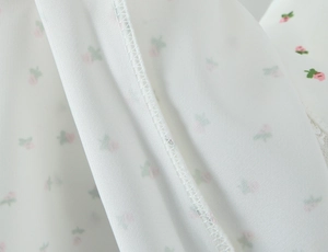 Gros plan sur une robe satinée fleurie montrant les feuilles vertes et la couture interne