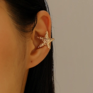 Detailed close-up of a golden starfish ear cuff with textured surface and spiral center