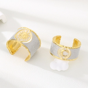 Detail of gold-edged cuff bracelet featuring silver glitter finish and white enamel sun moon