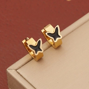 Close-up of golden butterfly hoop earrings with black enamel finish on a jewelry box