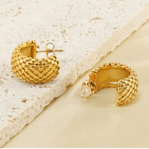 Détail macro de boucles d'oreilles dorées en C avec texture quadrillée sur soie