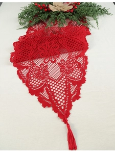Close-up of red lace Christmas table runner with tassels and festive pine branch decor