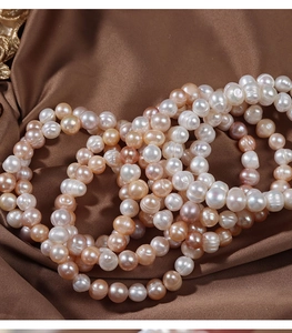 Macro shot of colorful natural freshwater pearls stacked on premium brown satin fabric