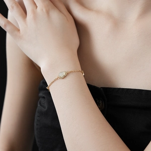 Close-up of gold chain bracelet featuring white clouded jade and pavé diamond details