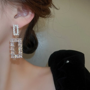 Macro shot of gold square earrings with cubic zirconia on model showing side details