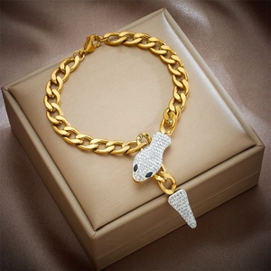 Detailed view of a golden Cuban link bracelet with a sparkling crystal snake head pendant