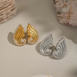 Sparkling crystal wing stud earrings in gold and silver finish on natural stone background