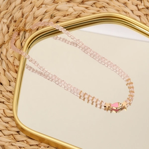 Detail of pink beaded necklace with fish pendant and gold stars on mirror base