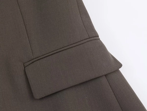 Detailed view of the flap pocket and twill texture on a dark brown tailored blazer