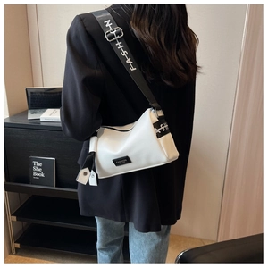 Back view of model wearing white pebbled leather bag with a wide black logo shoulder strap