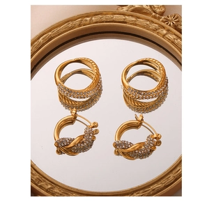 Detail of twisted gold ring and earring set with crystals on a vintage mirror surface