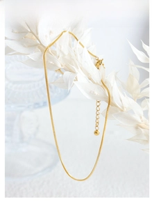 Detail of a minimalist gold snake chain anklet with an adjustable extension and secure clasp