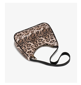 Close-up of leopard print baguette bag with black piping and gold zipper closure