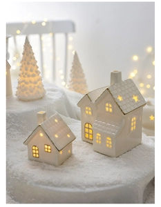 Detail eines weißen Keramik-Weihnachtshauses mit Goldrand und warmem LED-Lichteffekt