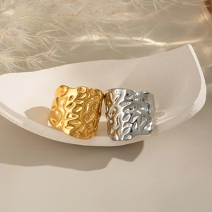 Geometric pleated gold and silver stainless steel rings on a white minimalist display