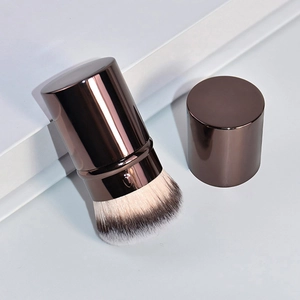 Dettaglio macro del pennello da trucco retrattile con setole dense e custodia in metallo bronzo