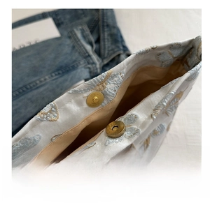 Macro detail of high-quality magnetic metal buckle on floral embroidery bucket bag