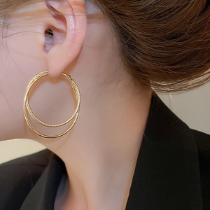 Detail of 18k gold plated double hoop earrings with textured and polished metal finish