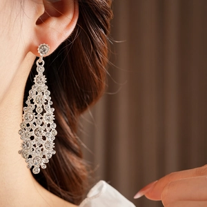 Primer plano de aretes largos plateados con diamantes de imitación en el modelo