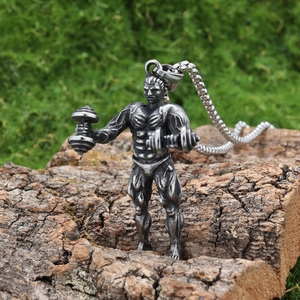 Détail macro du pendentif homme musclé avec haltères sur fond de texture bois naturel