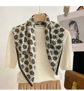 Detailed close-up of a white paisley silk scarf draped over a white knitted sweater