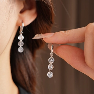 Detail of silver long tassel earrings with three zircon stones worn by a model